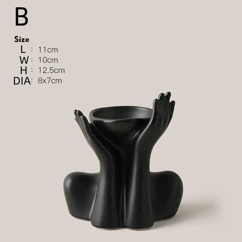 A black ceramic figural vase shaped like an artistic human hand or arm.