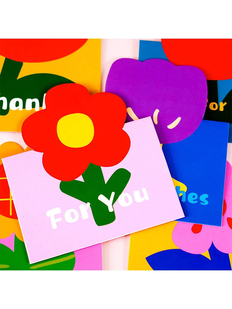 A colorful arrangement of mini flower thank you cards featuring bright red, purple, and yellow petals on a white background.