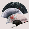 A vintage bamboo folding hand fan with black and white stripes and red floral accents.