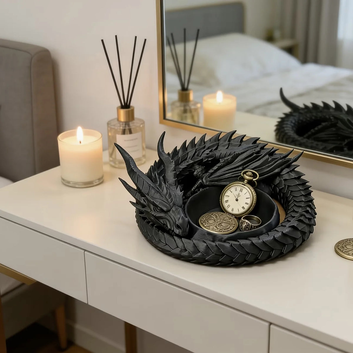 A black dragon-themed desktop storage tray organizer with gold accents sits on a white dresser next to a lit candle and a fra