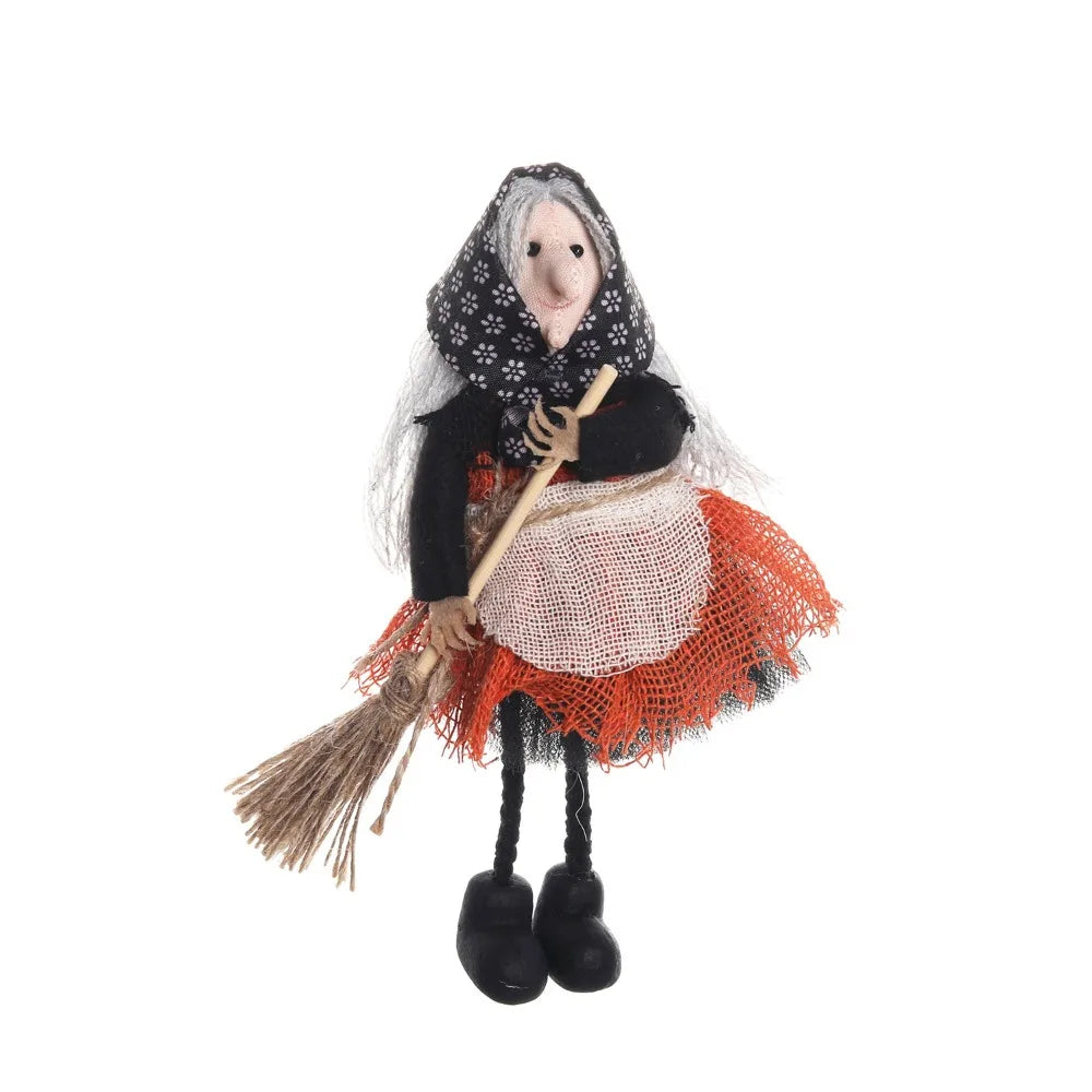 A scarecrow witch ornament featuring a face, black clothing, and an orange fabric skirt with straw accents.