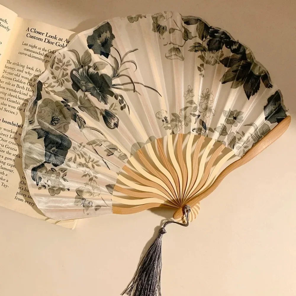 A folding hand fan with a leopard print design and a black handle is shown open against a light background.