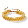 A bracelet made of small, round, yellow-orange citrine crystals strung together on a leather cord.