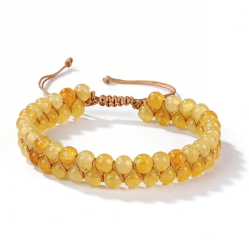 A bracelet made of small, round, yellow-orange citrine crystals strung together on a leather cord.