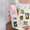 A pink cosmetic bottle with heart and animal stickers is held against a white background.