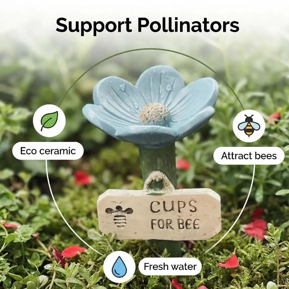 A light blue ceramic flower with a bee cup and a wooden tag for a bee watering station in a garden setting.