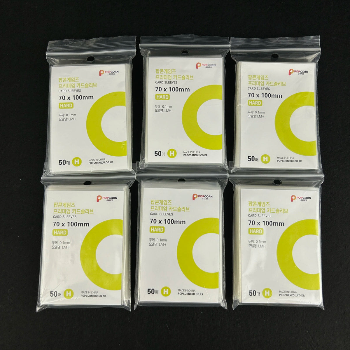 A set of 12 clear protective card sleeves in yellow and green packaging for cards.