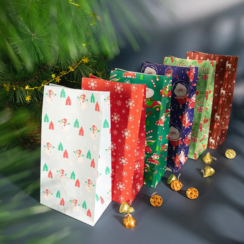 A collection of colorful Christmas kraft paper gift bags with seal stickers displayed in front of a green pine branch.