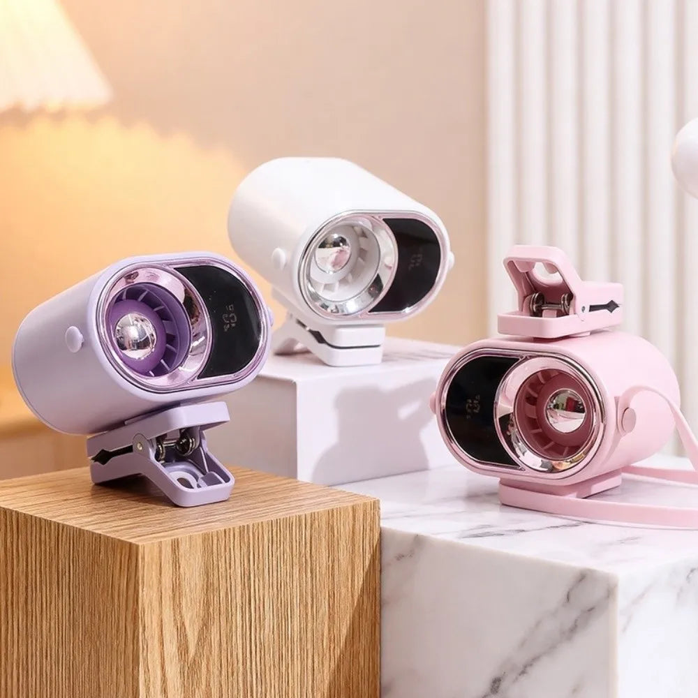 A pink and white adjustable clip-on mini electric fan is displayed on a wooden block and marble surface.