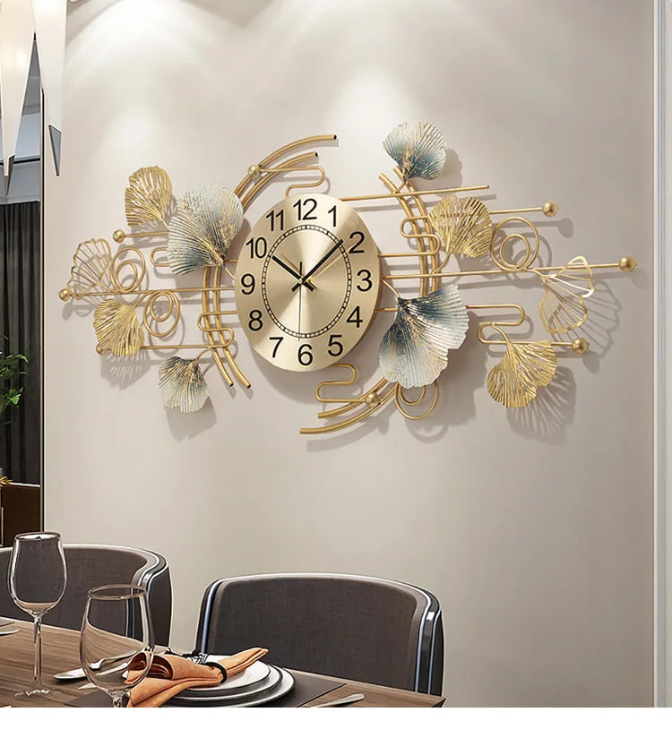 A decorative wall clock featuring a metal design of ginkgo leaves and branches on a light beige wall.