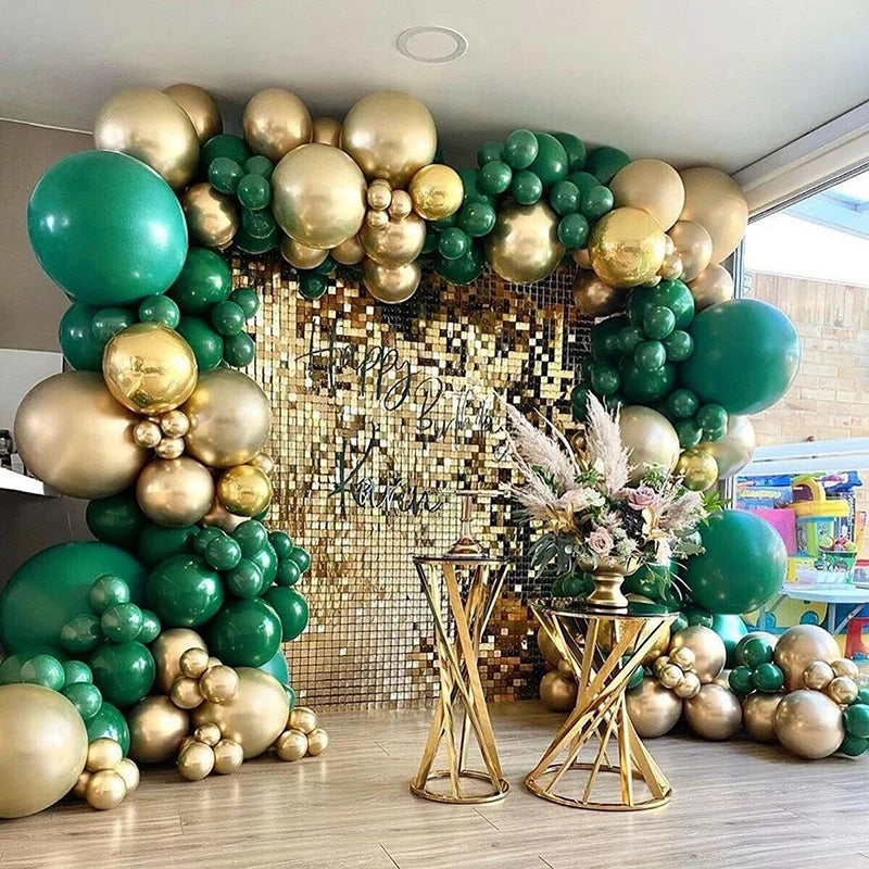 A balloon arch display featuring metallic gold and dark green balloons with floral accents.