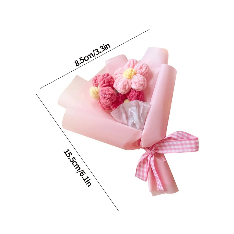 A pink handmade crochet sunflower mini bouquet wrapped in sheer pink paper and tied with a pink and white checkered ribbon.
