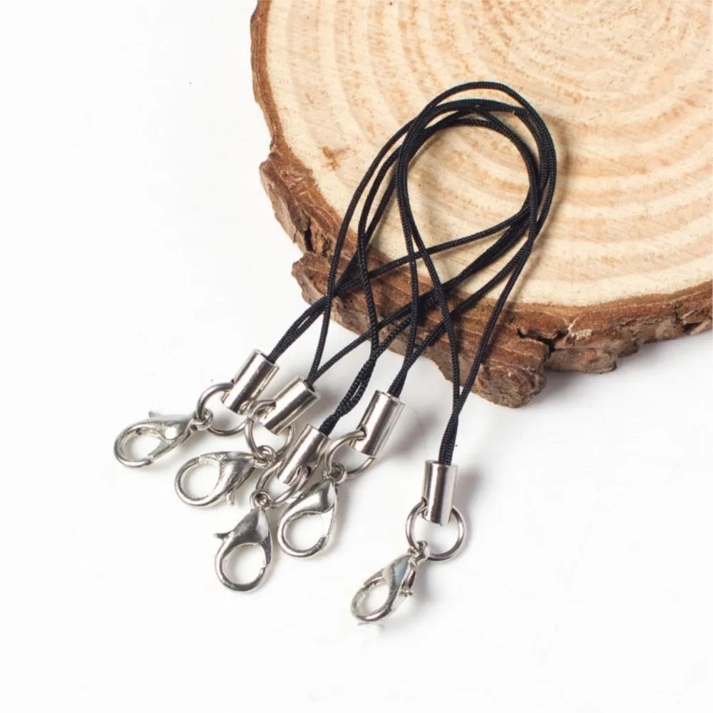Black lobster clasp lanyards and straps for jewelry making resting on a wooden slice