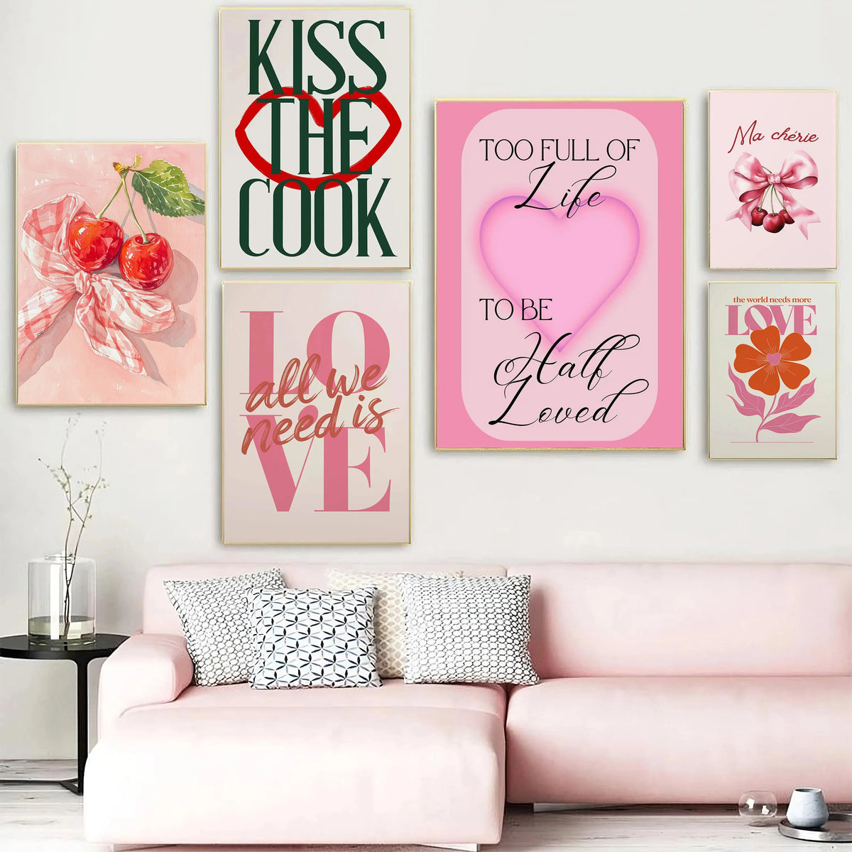 A gallery wall featuring pink and green art prints with text like Kiss The Cook and Too Full of Life