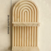 A wooden geometric wall shelf with a curved, ribbed design mounted on a wall.