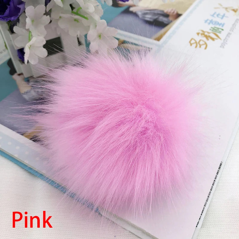 Pompon en fourrure synthétique rose et rose à l'enfilage, présenté sur fond blanc.
