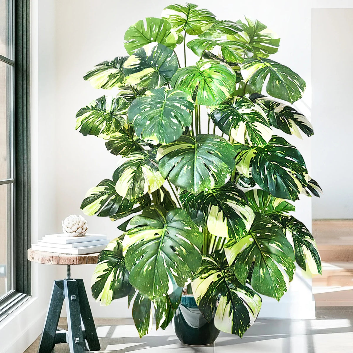 A large artificial monstera plant with green and white patterned silk leaves displayed indoors.