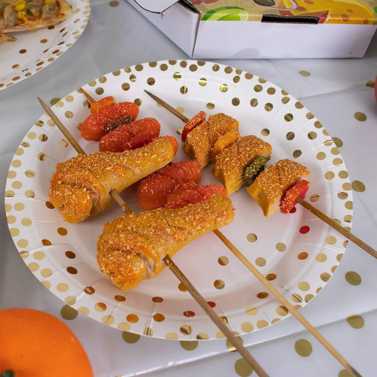 A plate of golden-fried food skewers with orange and red sauces on a white polka dot plate.