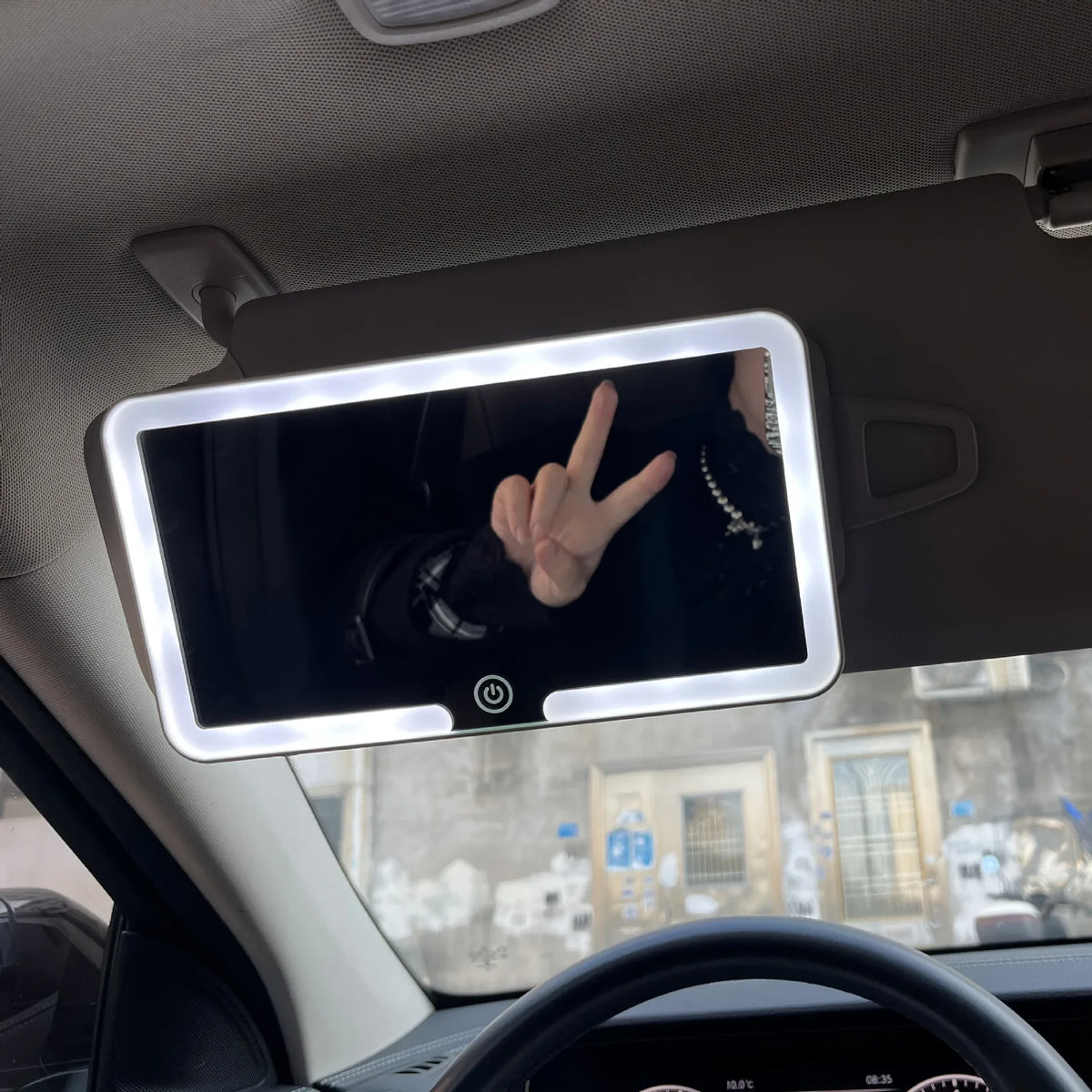A car sun visor vanity mirror with an LED light is visible inside a vehicle.