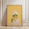 A painting of a frog wrapped in a towel on a yellow background.