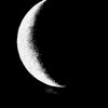 A minimalist black and white print of a crescent moon against a black background.