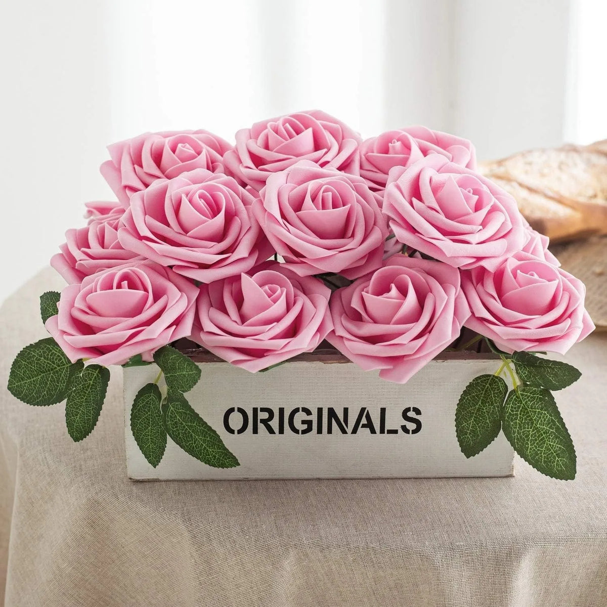 A bouquet of pink foam roses displayed in a wooden box with the word ORIGINALS on the side.