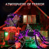 A spooky Halloween scene featuring a spider web illuminated by purple lights on the facade of a red house.