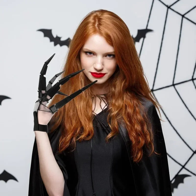 A woman with long red hair wearing black clothing and black articulated skeleton hand gloves against a dark background featur