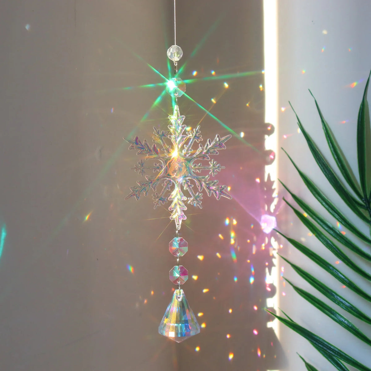 A hanging crystal rainbow wind chime decor featuring a sparkling snowflake and various glass elements.