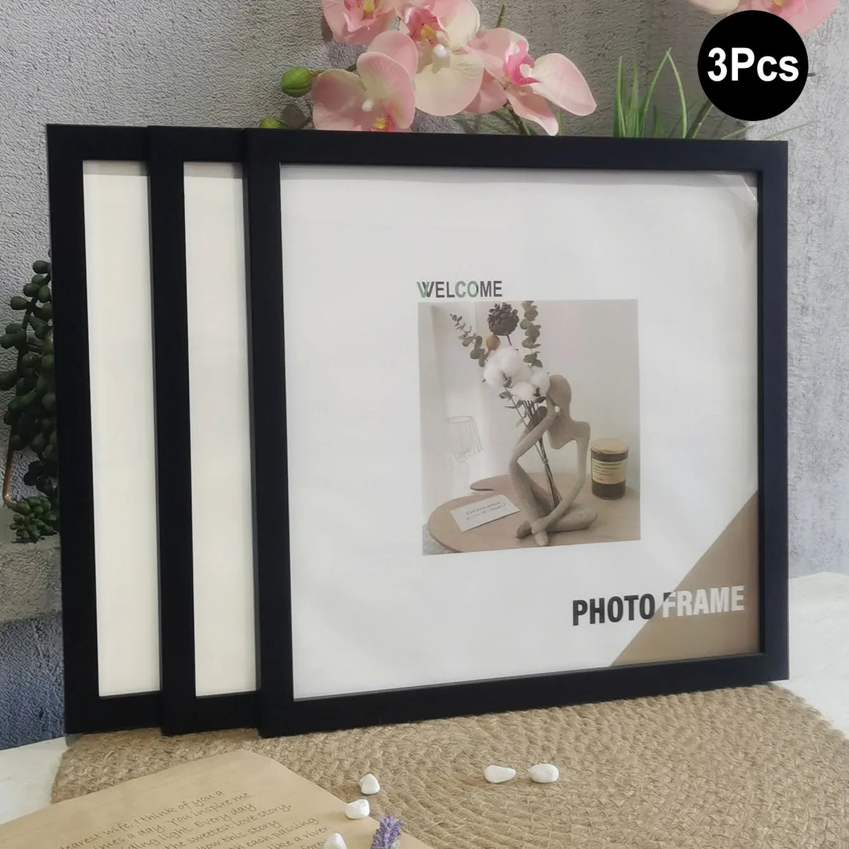 A set of three black photo frames with white mats and gold accents displayed on a beige surface.