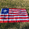 A decorative banner displaying the flag of Liberia spread out on green grass.