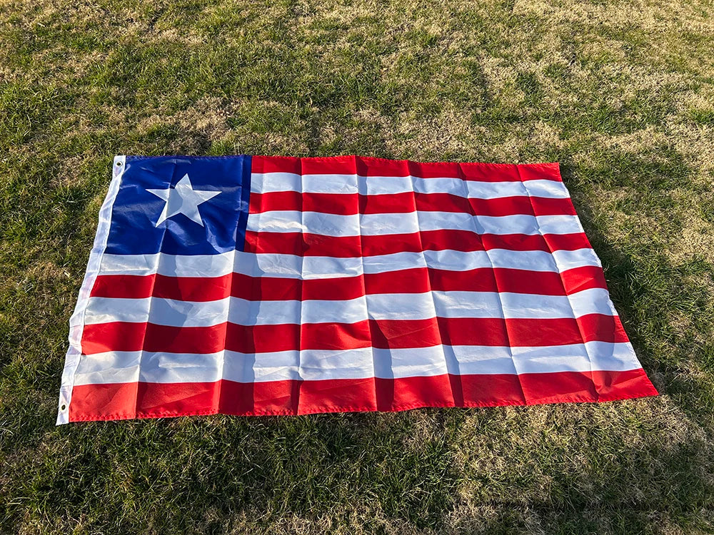 A decorative banner displaying the flag of Liberia spread out on green grass.