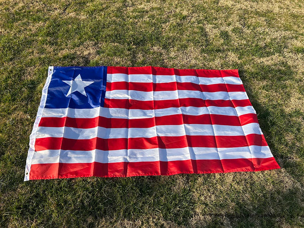 A decorative banner displaying the flag of Liberia spread out on green grass.