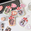 A collection of pink and green strawberry-themed bag keychains, card holders, and decorative items arranged on a white surfac