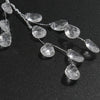 A delicate string of five clear crystal acrylic pendant ornaments laid on a dark surface.