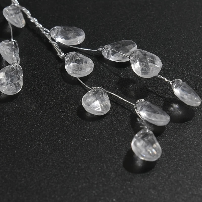 A delicate string of five clear crystal acrylic pendant ornaments laid on a dark surface.