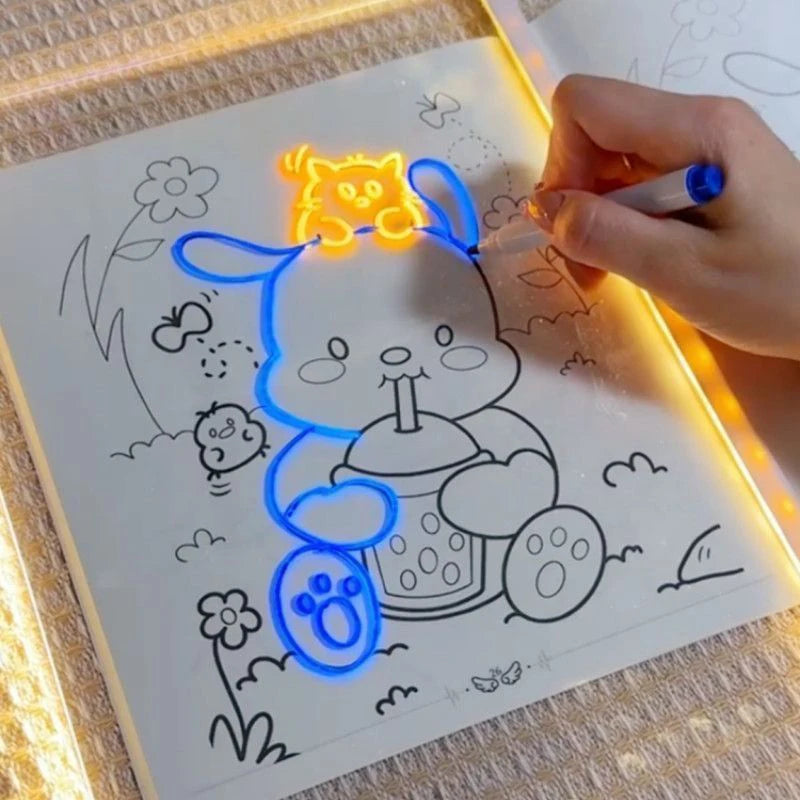يد ترسم قطة صفراء على لوحة رسم أكريليك مضيئة بأقلام، تضيء العمل الفني.