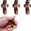 A hand holds a small wooden cross with an epoxy heart detail.