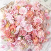 A dense arrangement of pink, peach, and cream silk artificial flower heads for crafts and decor.