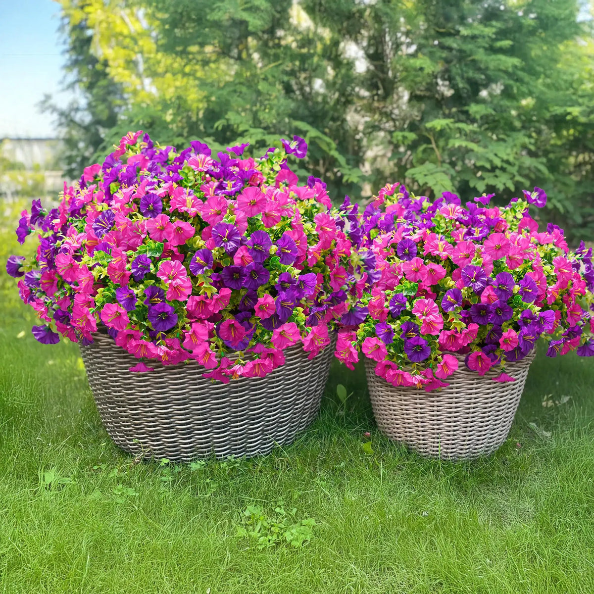 Two woven baskets filled with vibrant pink and purple artificial silk flowers on a green lawn.