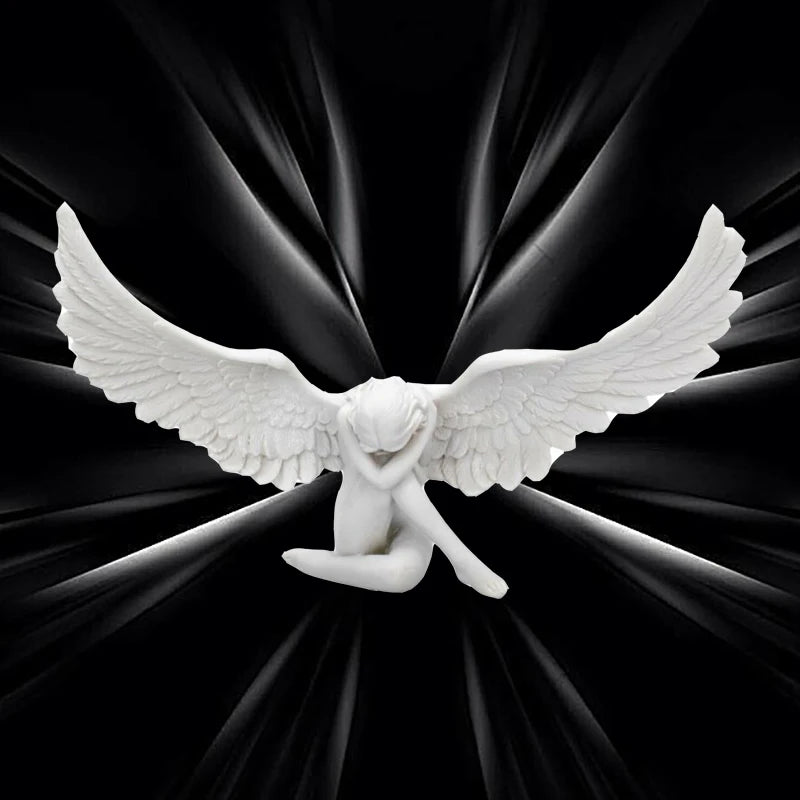 A white resin angel wing figurine with a serene face spreads out against a dark, radiating background.