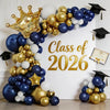 A balloon arch display featuring navy blue, white, and gold balloons arranged in a crown shape for a graduation theme.