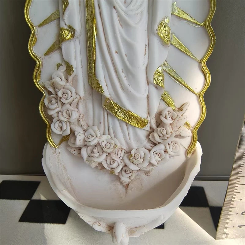 White resin Virgin Mary holy water wall decor featuring gold accents and a floral wreath