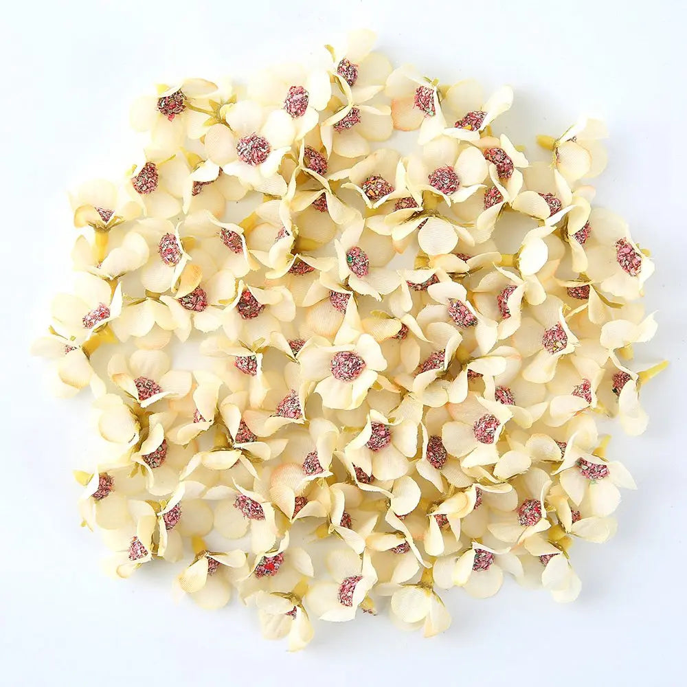A pile of small, pale yellow silk artificial flower heads with pink accents.