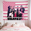 A pink American flag tapestry featuring stars and stripes hanging above a white bed with pink bedding.