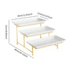A three-tier rectangular serving platter stand with white ceramic plates and gold-colored metal legs.
