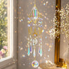 A hanging crystal prism suncatcher with a gold geometric frame and dangling clear crystals.
