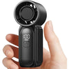 A black portable handheld cooling fan with a mesh grille and a power button is held in a person's hand.