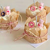 Several paper cupcake liners are decorated with pink teddy bears and candy rings, tied with red and white twine.