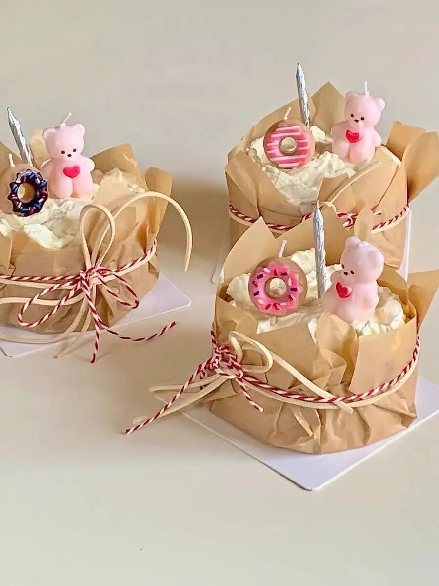 Several paper cupcake liners are decorated with pink teddy bears and candy rings, tied with red and white twine.